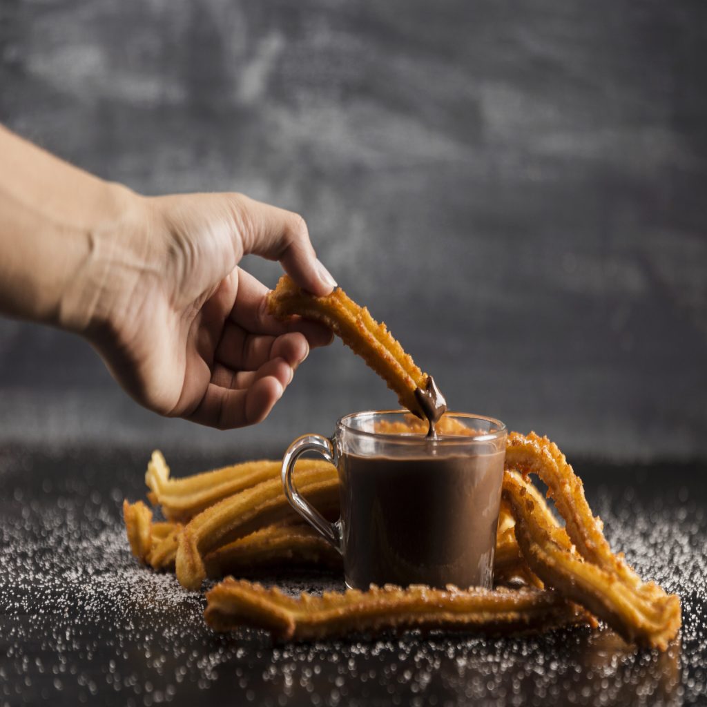 delicious-churros-with-melted-chocolate-on-table Churros con chocolate